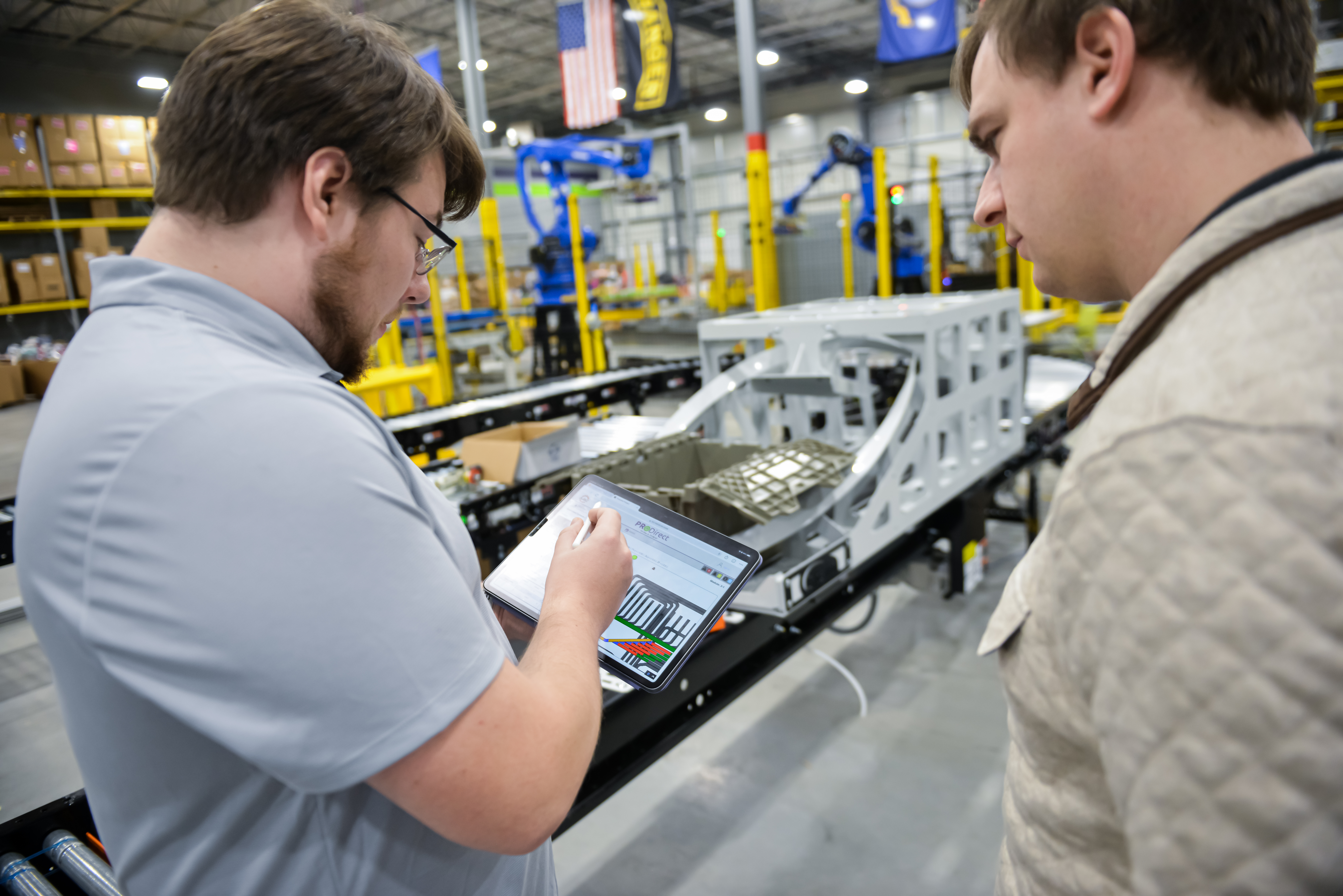 Sean pointing out something to CJ using tablet in warehouse